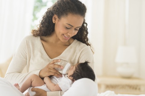 Hispanic mother feeding newborn baby