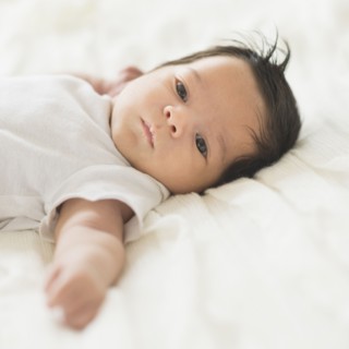Hispanic baby laying on cot