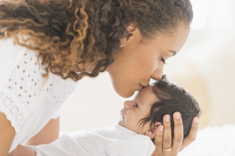 Hispanic mother kissing baby's forehead