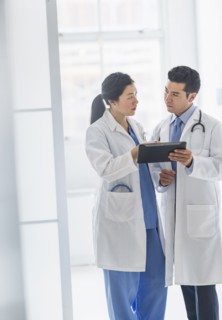 Doctors using digital tablet in hospital corridor