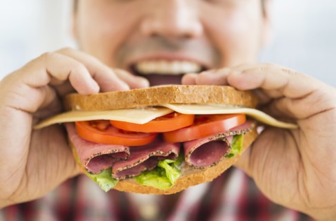 Mixed race man eating sandwich