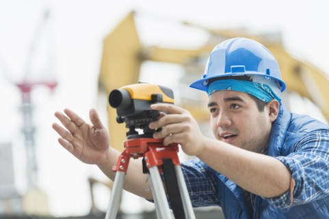 Mixed race engineer using theodolite at construction site