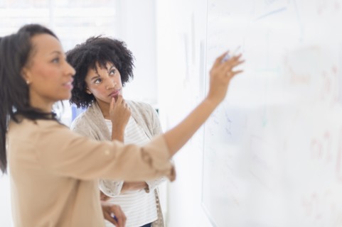 African American businesswomen at whiteboard in office