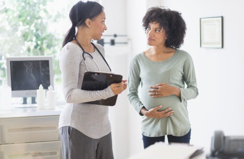 African American doctor talking to pregnant woman