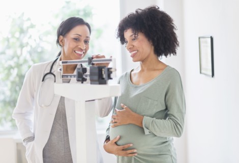 African American doctor weighing pregnant woman