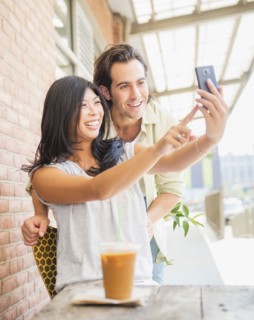 Couple taking self-portrait at sidewalk cafe