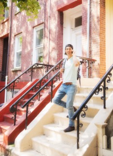 Caucasian man on front stoop of urban brownstone