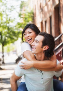 Man carrying girlfriend piggyback on urban sidewalk
