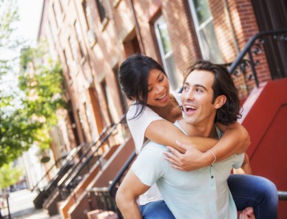 Man carrying girlfriend piggyback outside brownstones