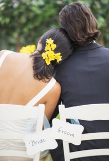 Newlywed couple sitting at wedding reception outdoors