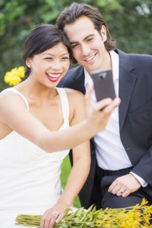 Newlywed couple taking self-portrait at wedding reception