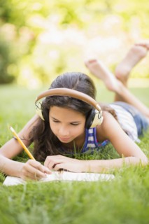 Mixed race girl listening to headphones and drawing outdoors