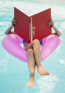 Mixed race girl reading in swimming pool