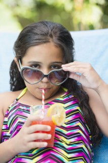 Mixed race girl sipping juice at poolside