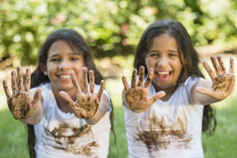 Mixed race girls covered in mud outdoors