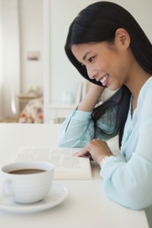 Chinese woman reading with cup of coffee