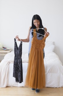 Chinese woman picking out dresses in bedroom