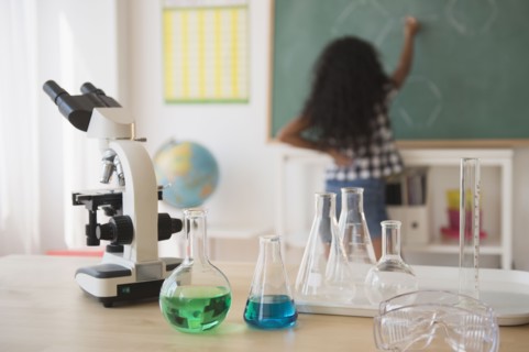 Mixed race student writing on chalkboard in classroom