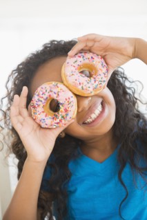 Mixed race girl holding donuts over her eyes