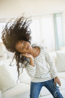 Mixed race girl dancing to headphones in living room