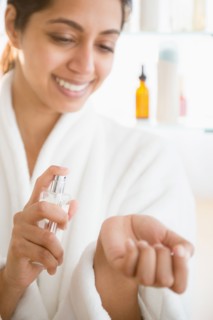 Close up of Asian woman spraying perfume on wrist