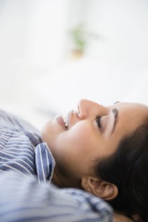 Close up of serene Asian woman laying with hands behind head