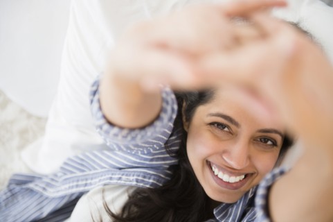 Close up portrait of smiling Asian woman laying in bed