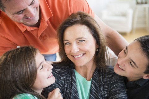 Caucasian man and children smiling at woman