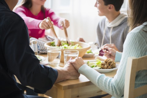 Caucasian parents holding hands at table