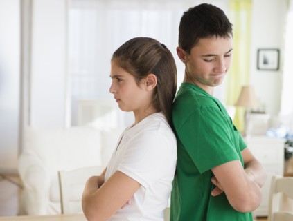 Angry Caucasian brother and sister standing back to back
