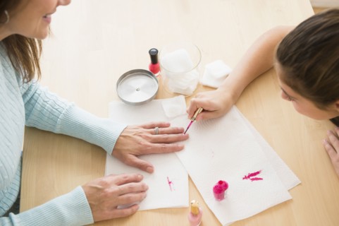 Caucasian girl giving mother a manicure