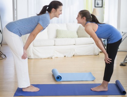 Caucasian mother and daughter practicing yoga in living room