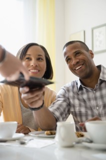 Couple receiving bill from waitress in restaurant
