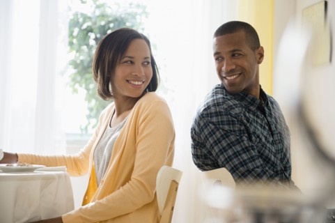 Man and woman turning to smile at each other in restaurant