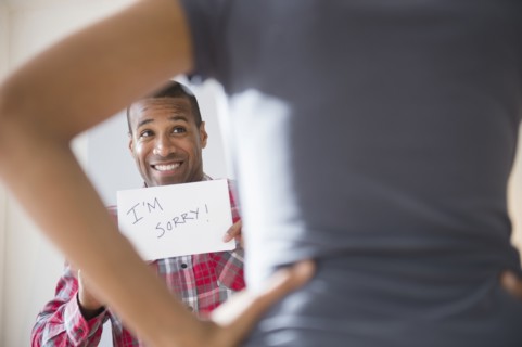 Man showing 'I'm Sorry' sign to angry girlfriend