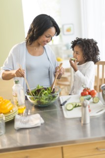 African American mother and daughter tossing salad