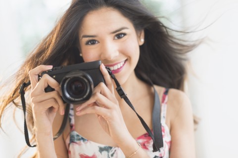 Portrait of smiling Hispanic woman holding digital camera