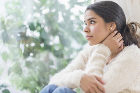 Pensive Hispanic woman looking out window