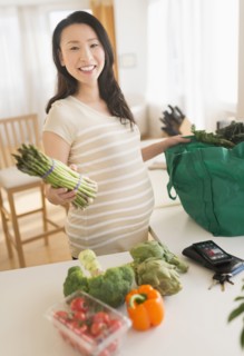 Portrait of pregnant Japanese woman unloading groceries