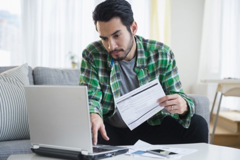 Mixed race man paying bills in living room