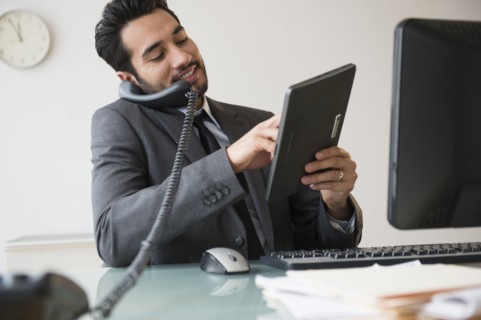 Mixed race businessman using digital tablet on telephone