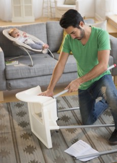 Father setting up highchair in living room