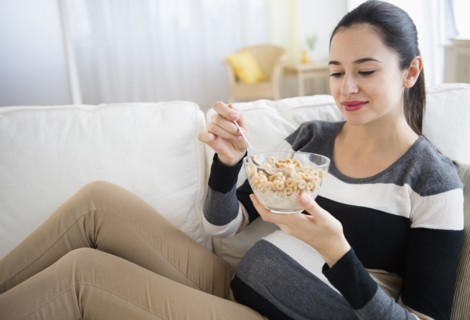 Pregnant Caucasian woman eating on sofa