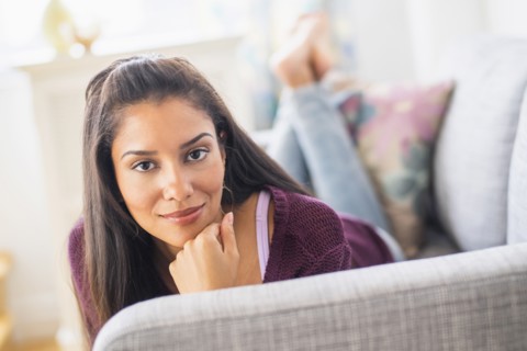 Hispanic woman laying on sofa