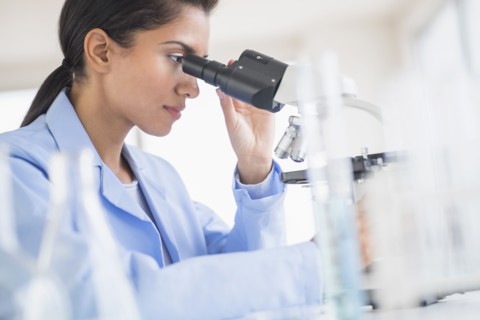 Hispanic scientist using microscope in laboratory