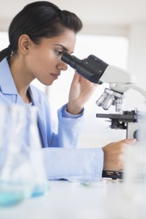 Hispanic scientist using microscope in laboratory