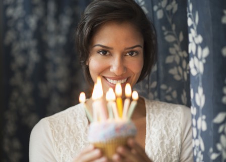 Hispanic woman holding birthday cupcake