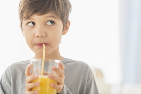 Hispanic boy drinking juice with straw