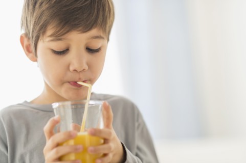Hispanic boy drinking juice with straw