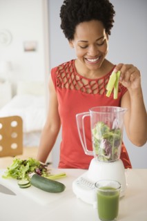 Black woman making green smoothies in blender